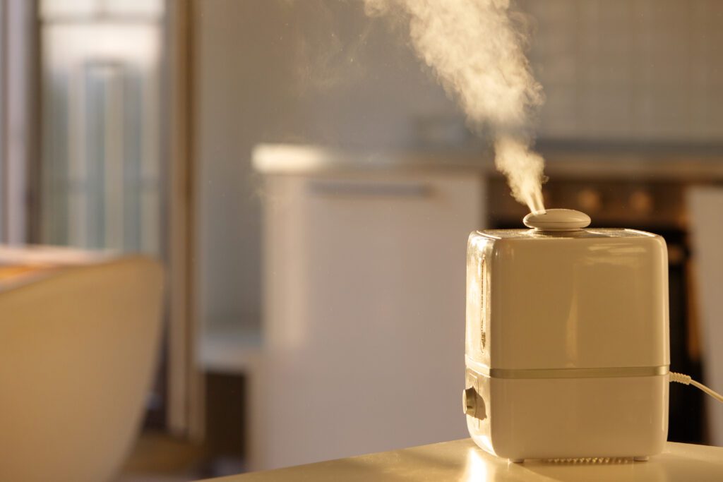 Close up of aroma oil diffuser on the table at home, steam from the air humidifier. Ultrasonic technology, increase in air humidity indoors, comfortable living conditions.