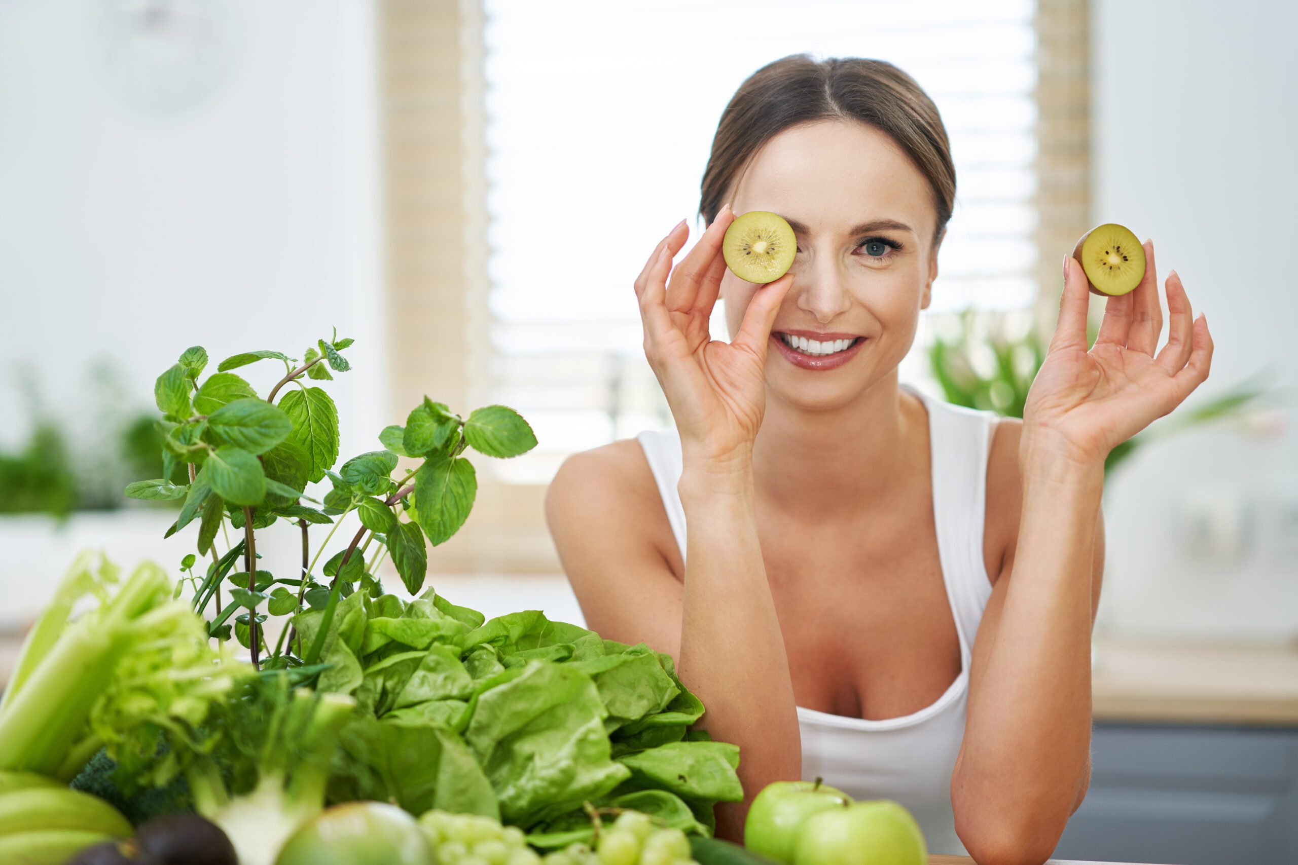 Picture of healthy adult woman with green food in the kitchen